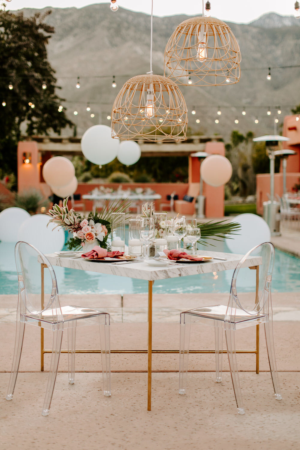 sweetheart table with ghost chairs, marble table and pink tropical accents