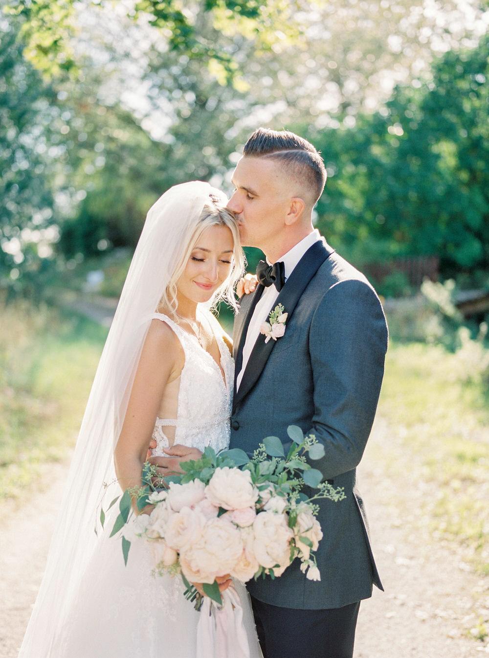 groom tenderly kisses his bride's head